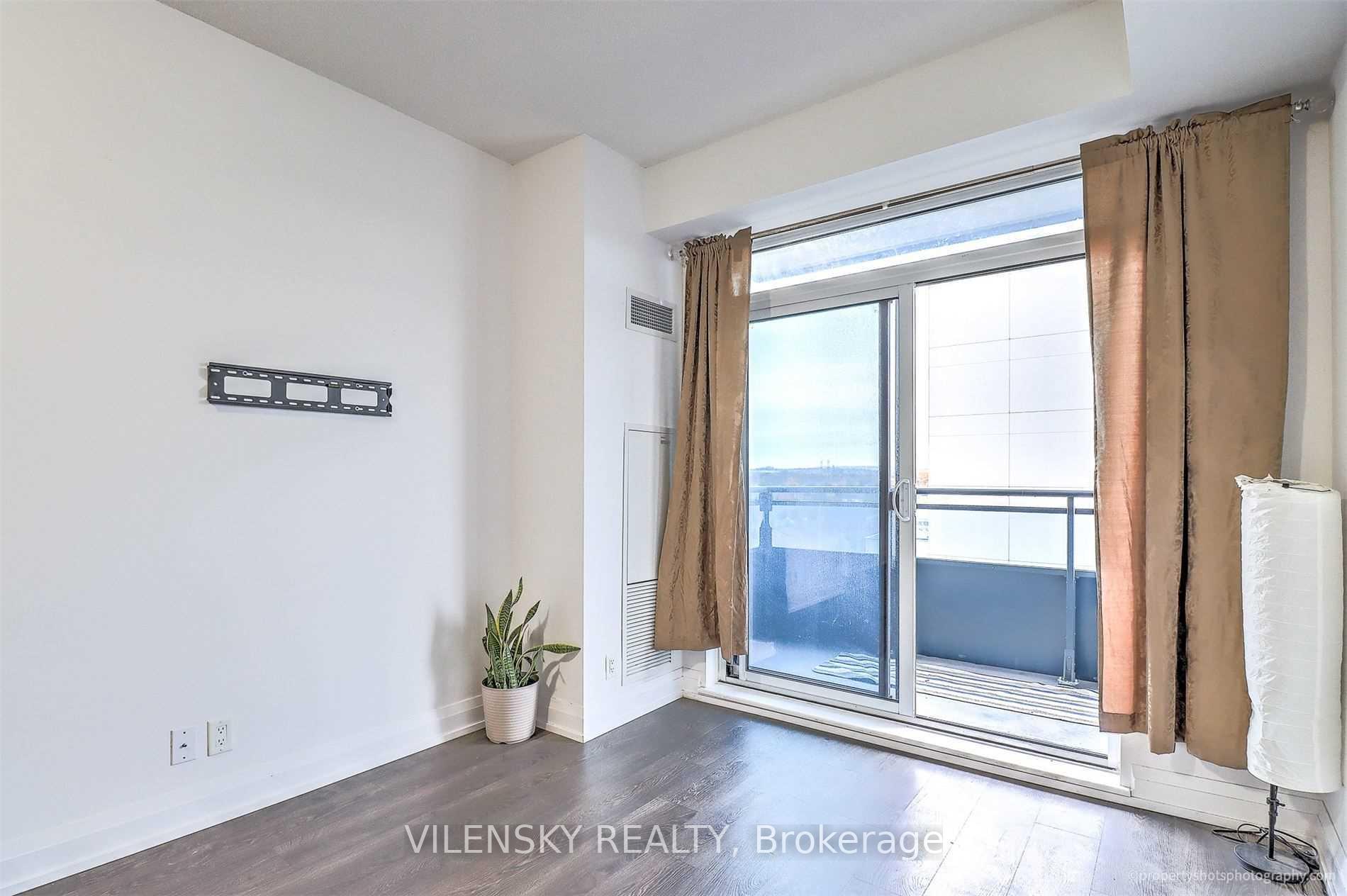 Bright condo room with sliding glass doors to a balcony and a wall-mounted TV bracket.
