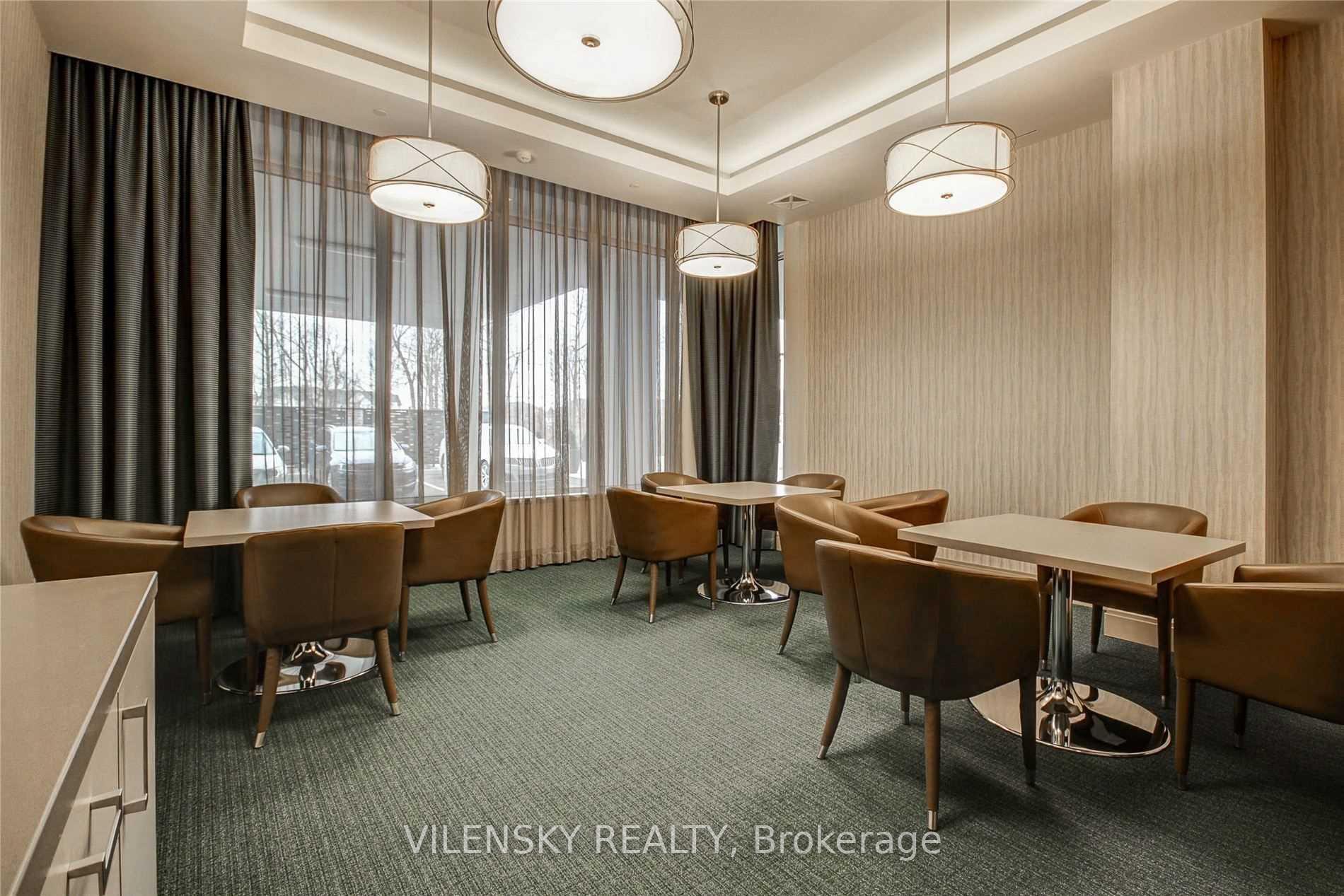 Condominium dining room with brown chairs, multiple tables, and large curtained windows.