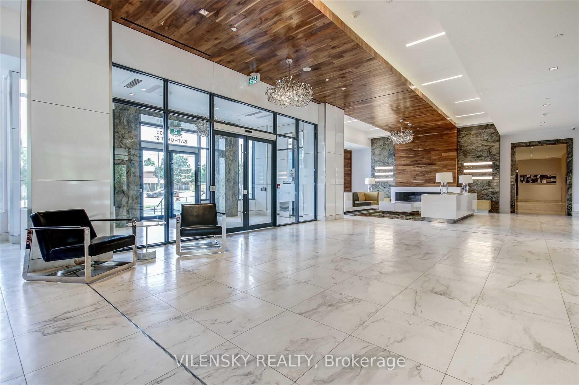 Condominium lobby with marble-look floors, wood ceiling, glass entrance, and contemporary seating.