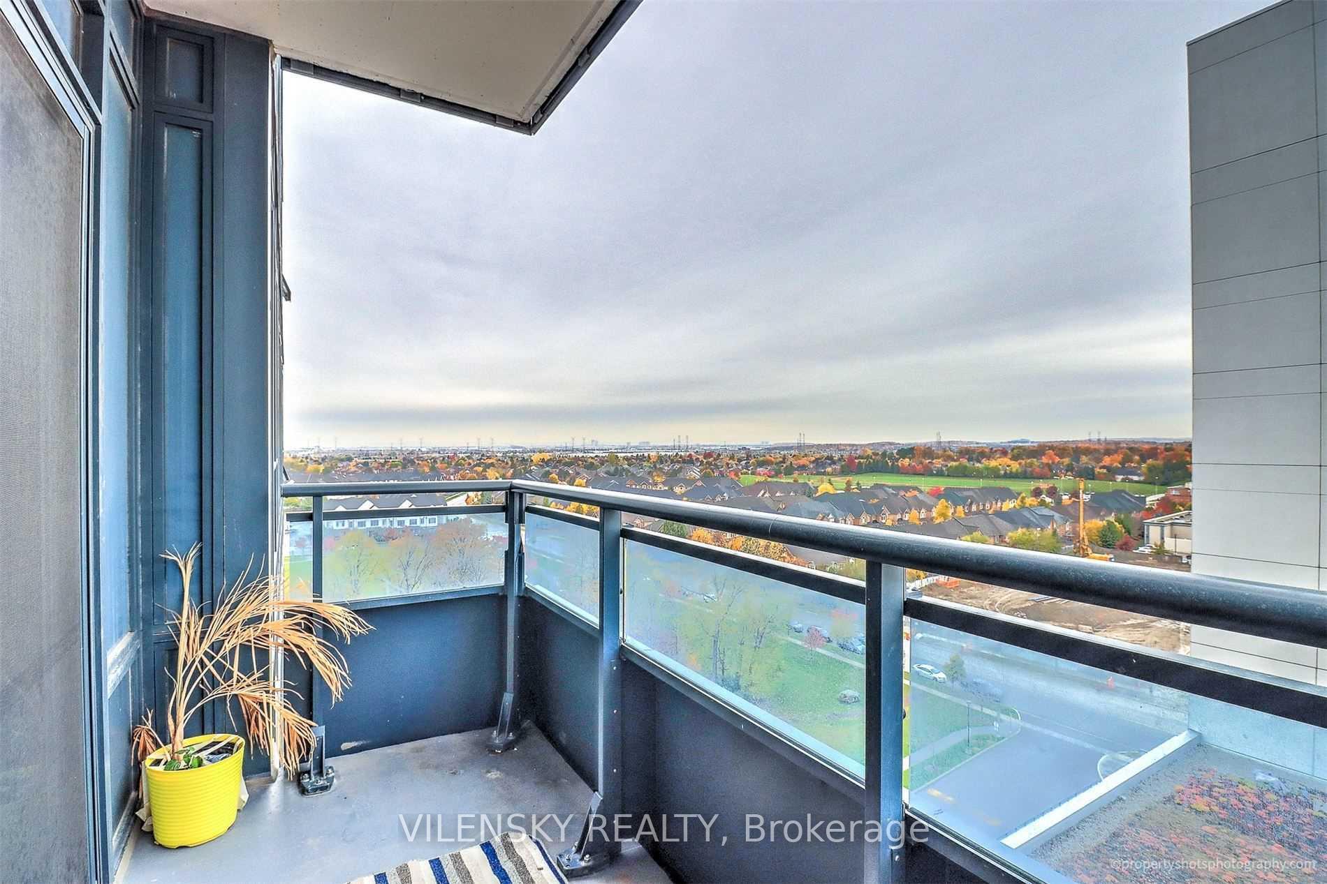 Condo balcony overlooking autumn-colored homes and a green sports field.