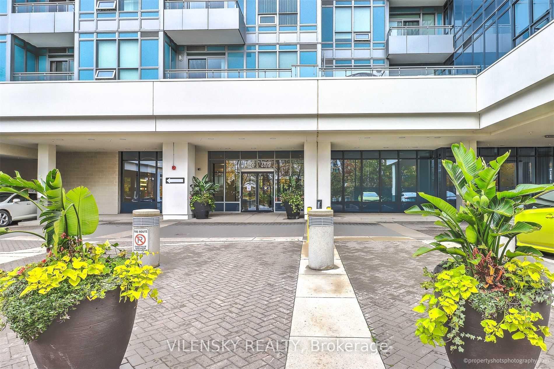 Condominium entrance at 7890 Bathurst Street, framed by large planters beneath blue-tinted windows and balconies.