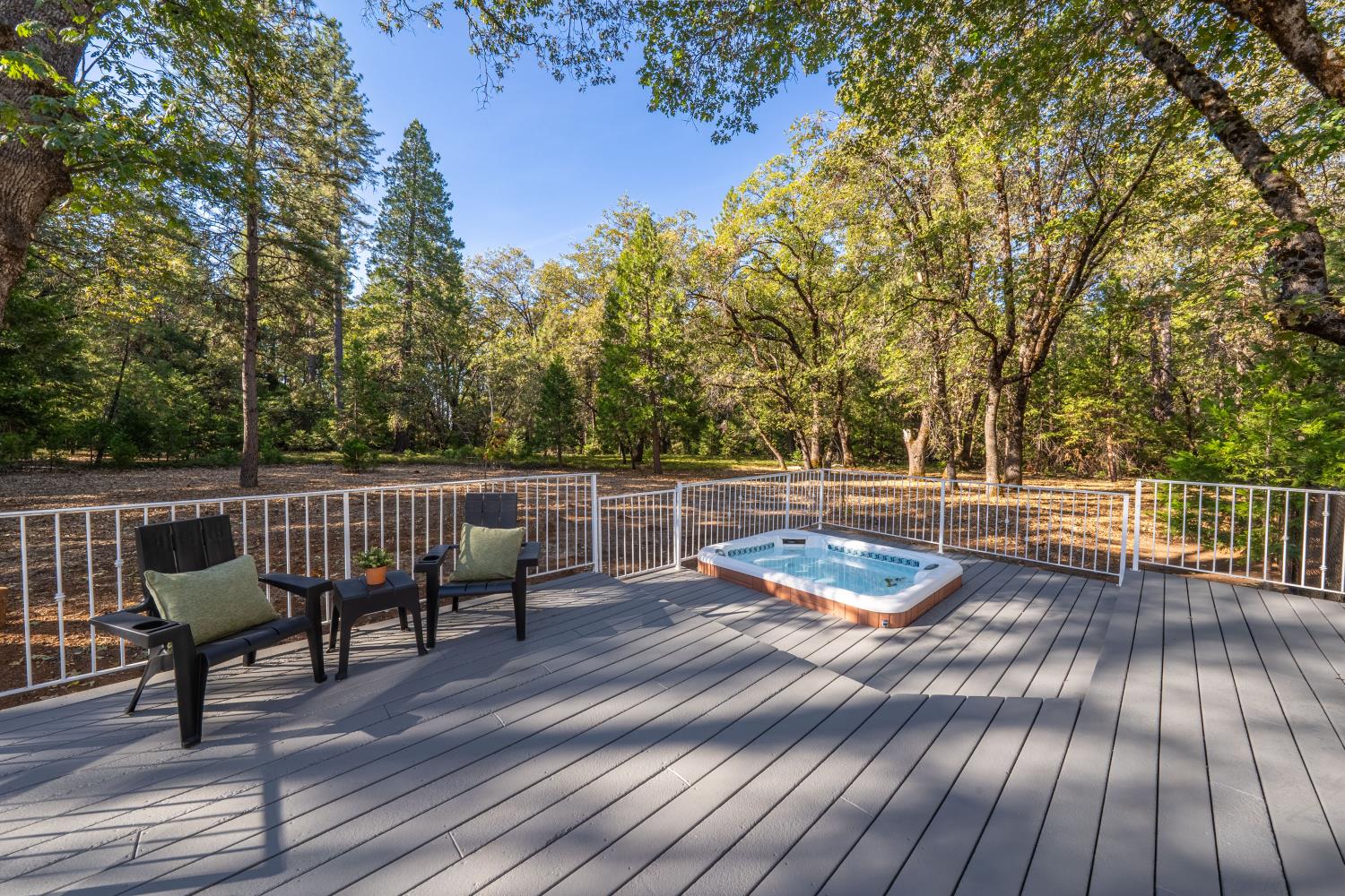 Wooded backyard deck with a hot tub and seating.