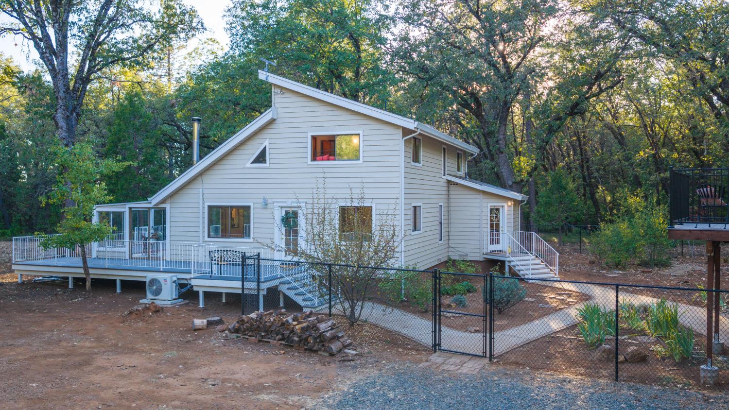 Two-story house with broad decks and exterior stairs surrounded by mature trees.