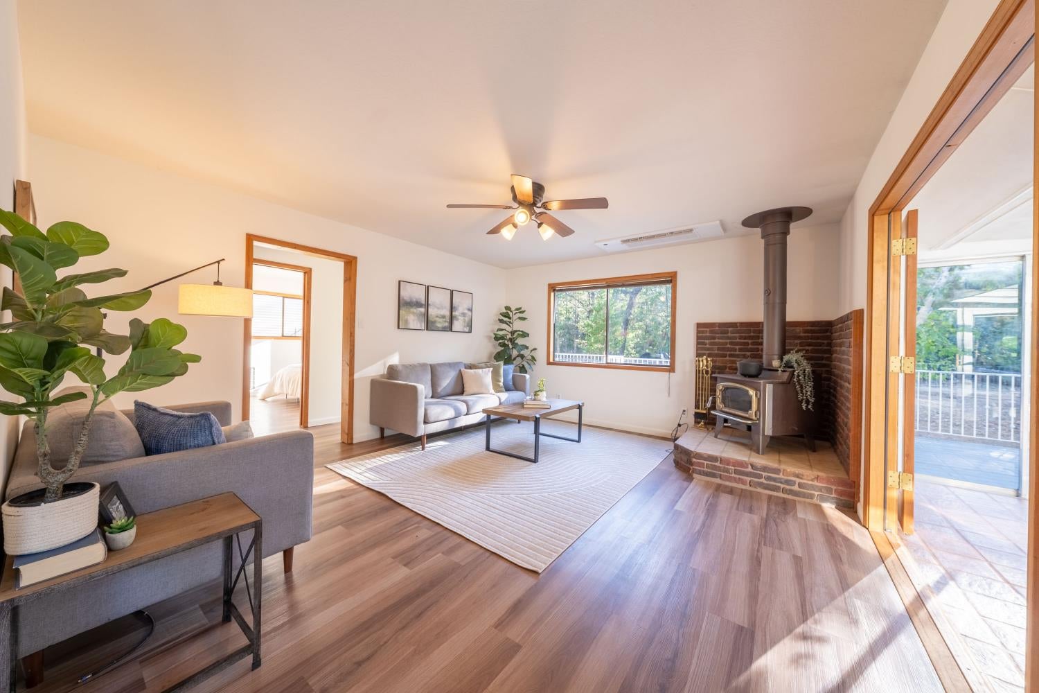 Living room with gray sofas, wood floors, and a wood-burning stove beside a brick hearth.