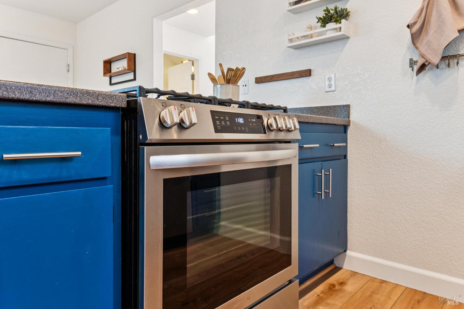 Kitchen with blue cabinets, dark countertops, and a stainless steel range.