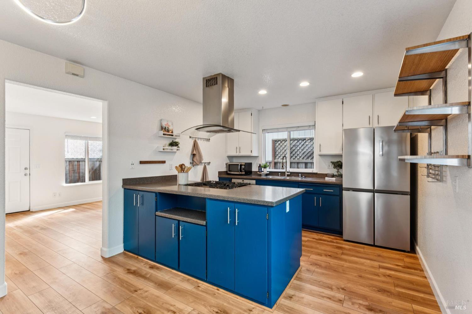 Kitchen with vivid blue cabinets, a large gray-countertop island, and stainless steel appliances.