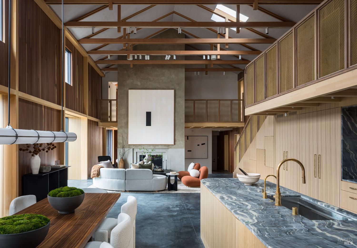 Open-plan kitchen and living room with a stone island, timber trusses, and a mezzanine.