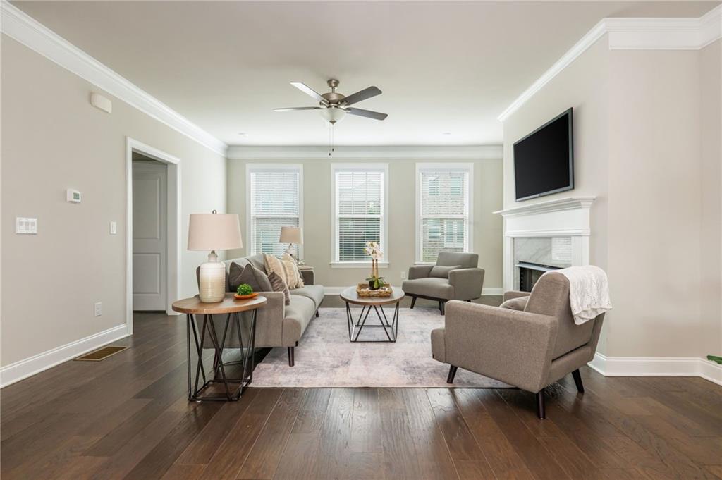 Furnished living room with a fireplace, mounted television, and three windows.