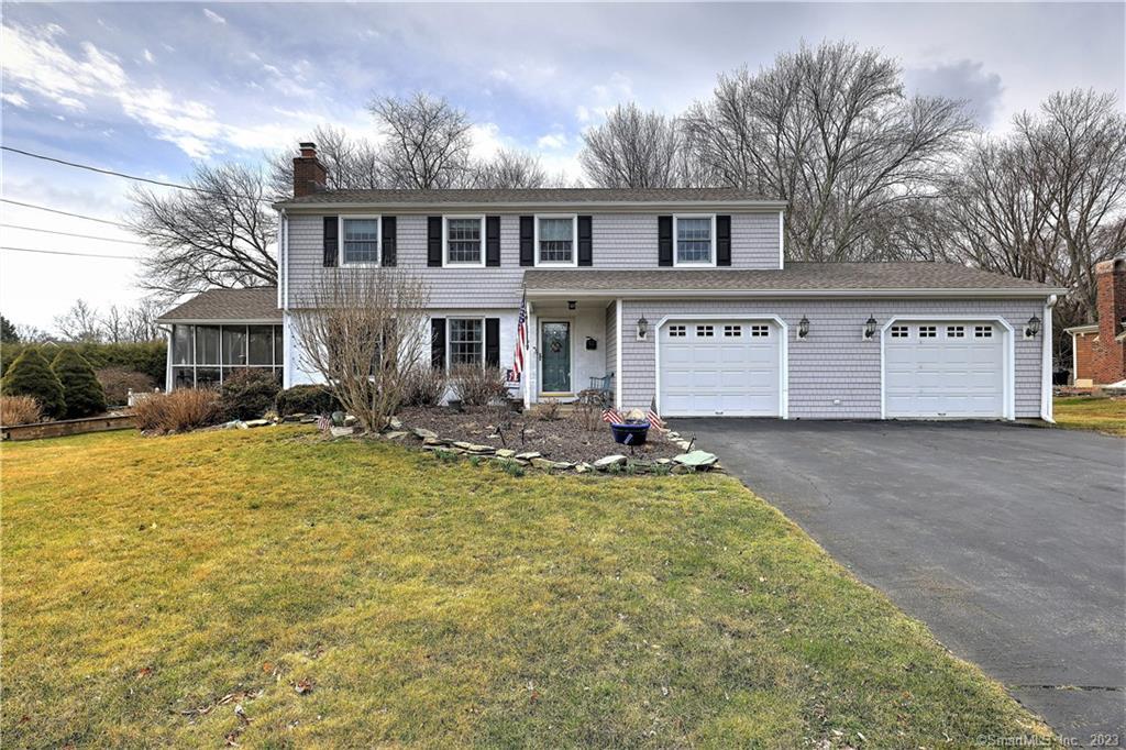 Gray split-level home with an attached two-car garage, enclosed porch, and broad driveway.