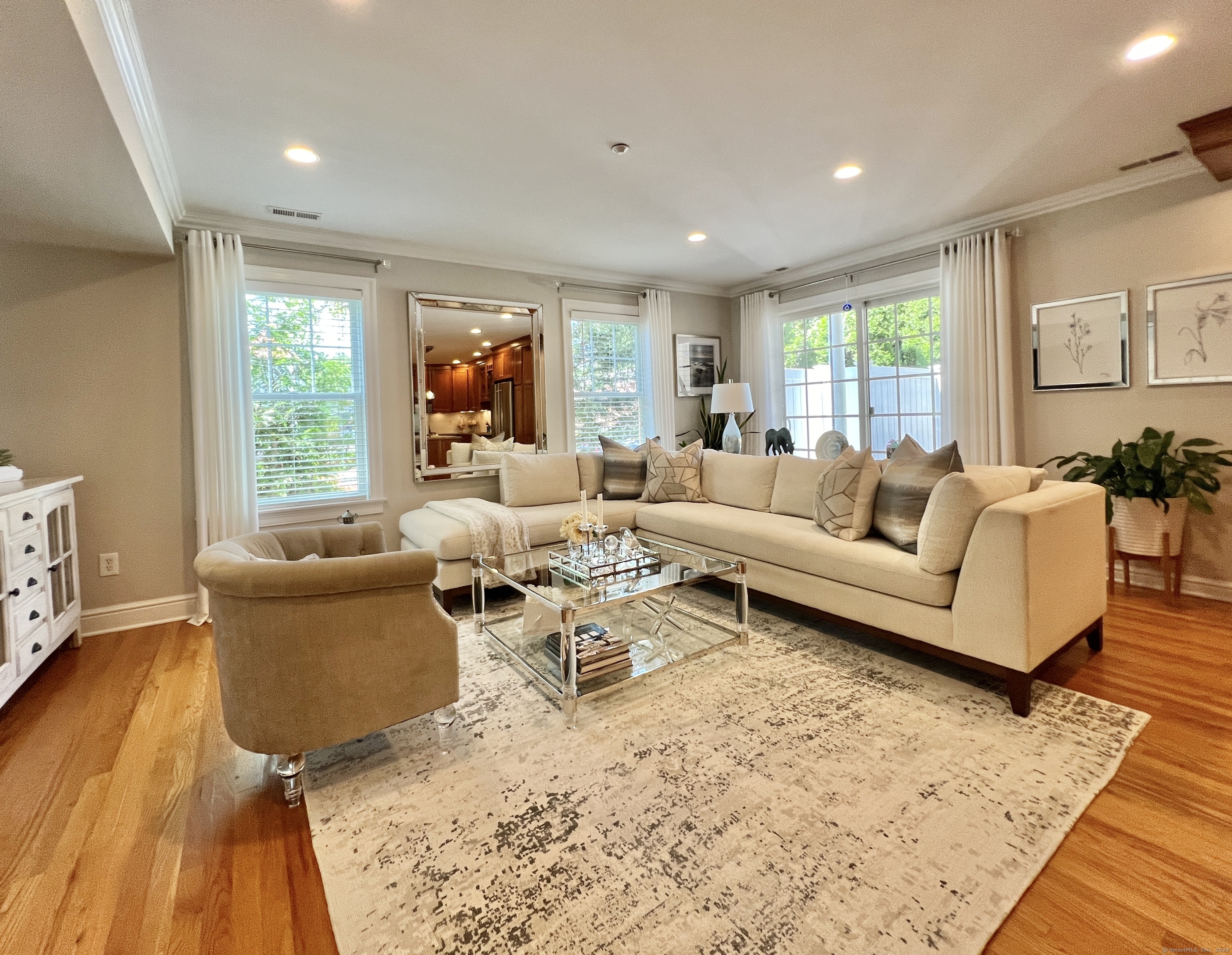 Furnished living room with a cream sectional, glass coffee table, and large patterned rug.