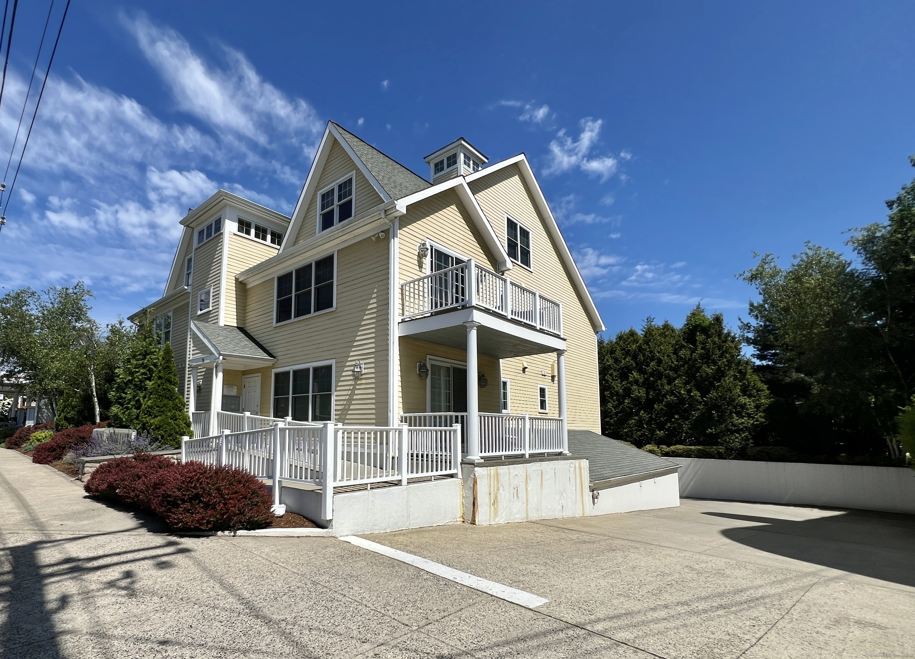 Pale yellow multi-story house with white trim, gabled roof, and elevated porches.