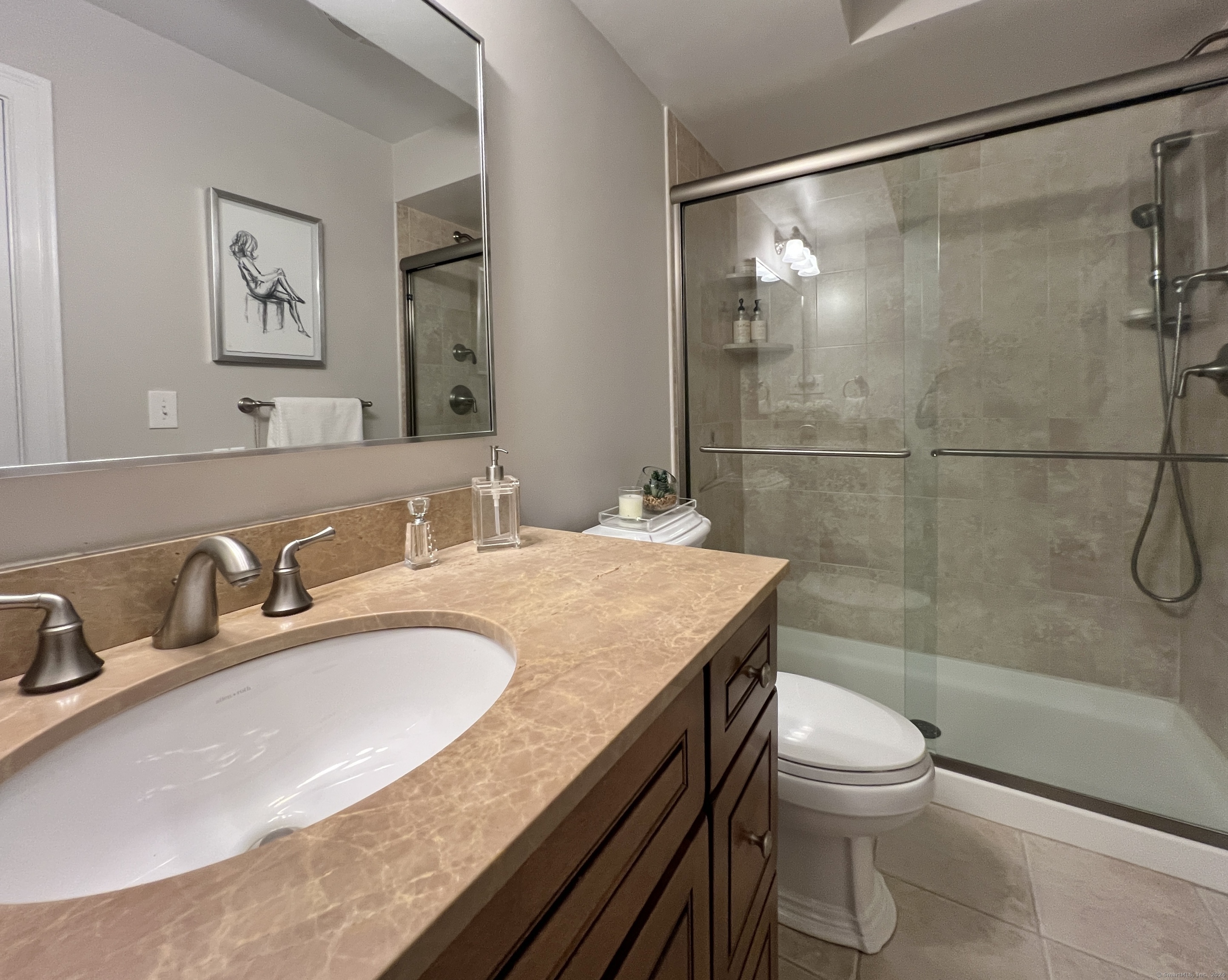 Bathroom with a stone vanity, dark wood cabinetry, and a glass-enclosed tiled shower.