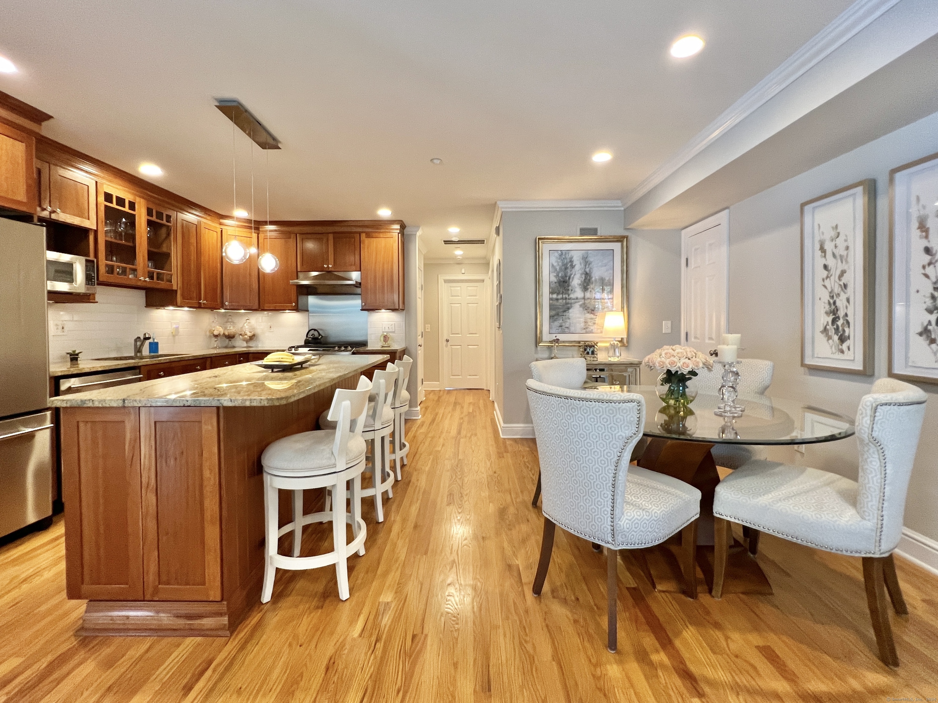 Open kitchen and dining area with a granite island, wood cabinetry, and hardwood floors.