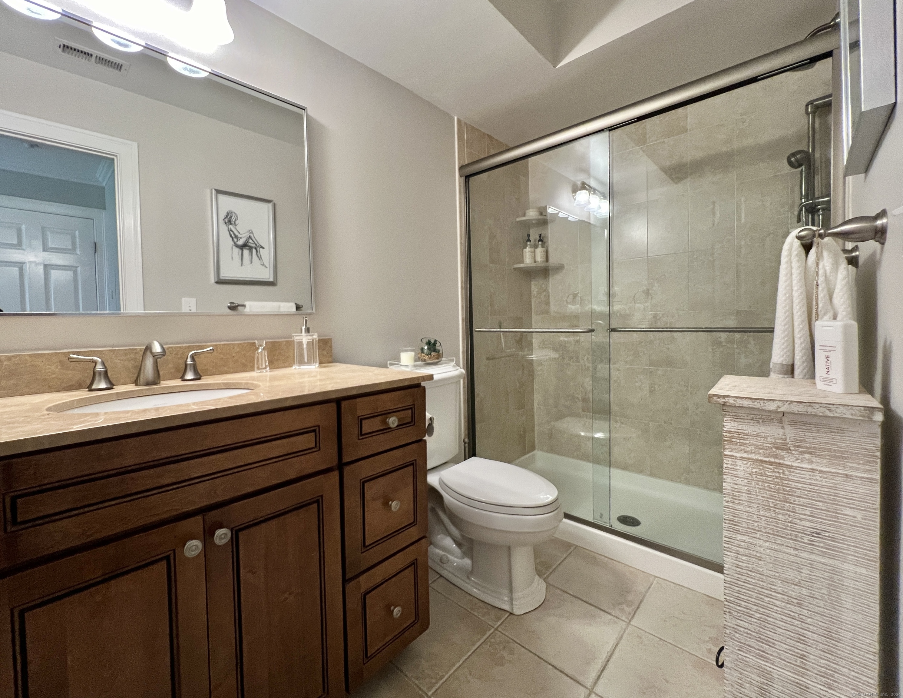 Bathroom with a dark wood vanity and a glass-enclosed tiled shower.