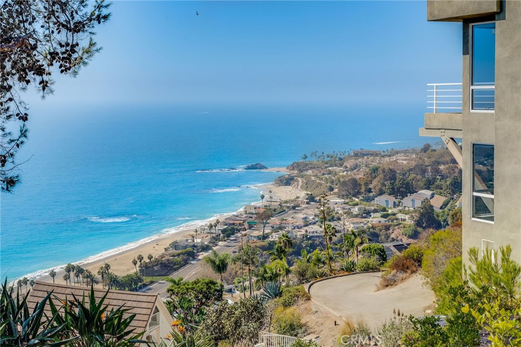 Coastal homes and shoreline beneath a wide ocean view, seen from a Newport Coast hillside.