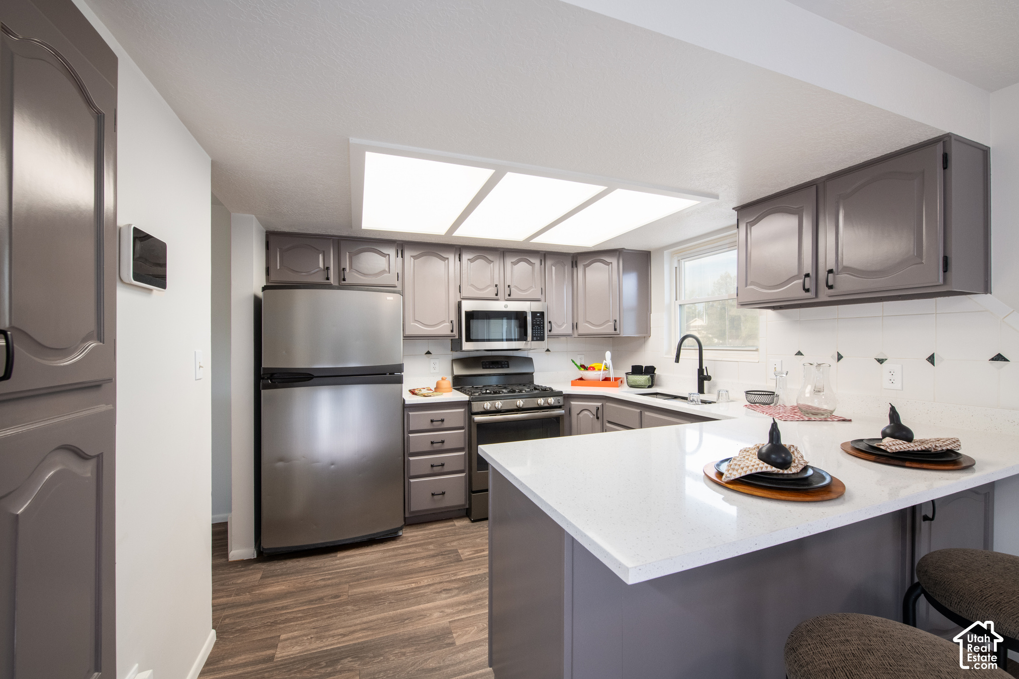 Kitchen with gray cabinets, stainless steel appliances, and a large white island.