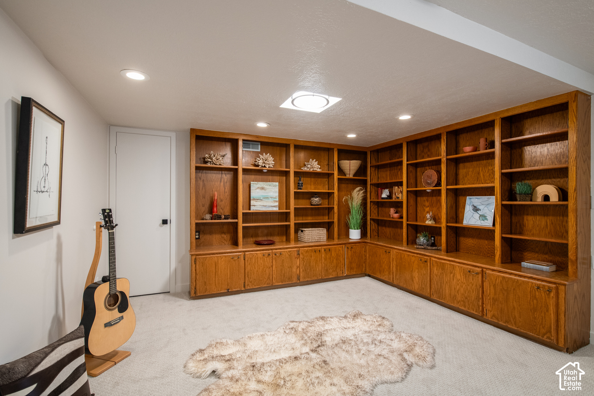 Den with wraparound wood built-ins, a guitar, and a light shag rug.