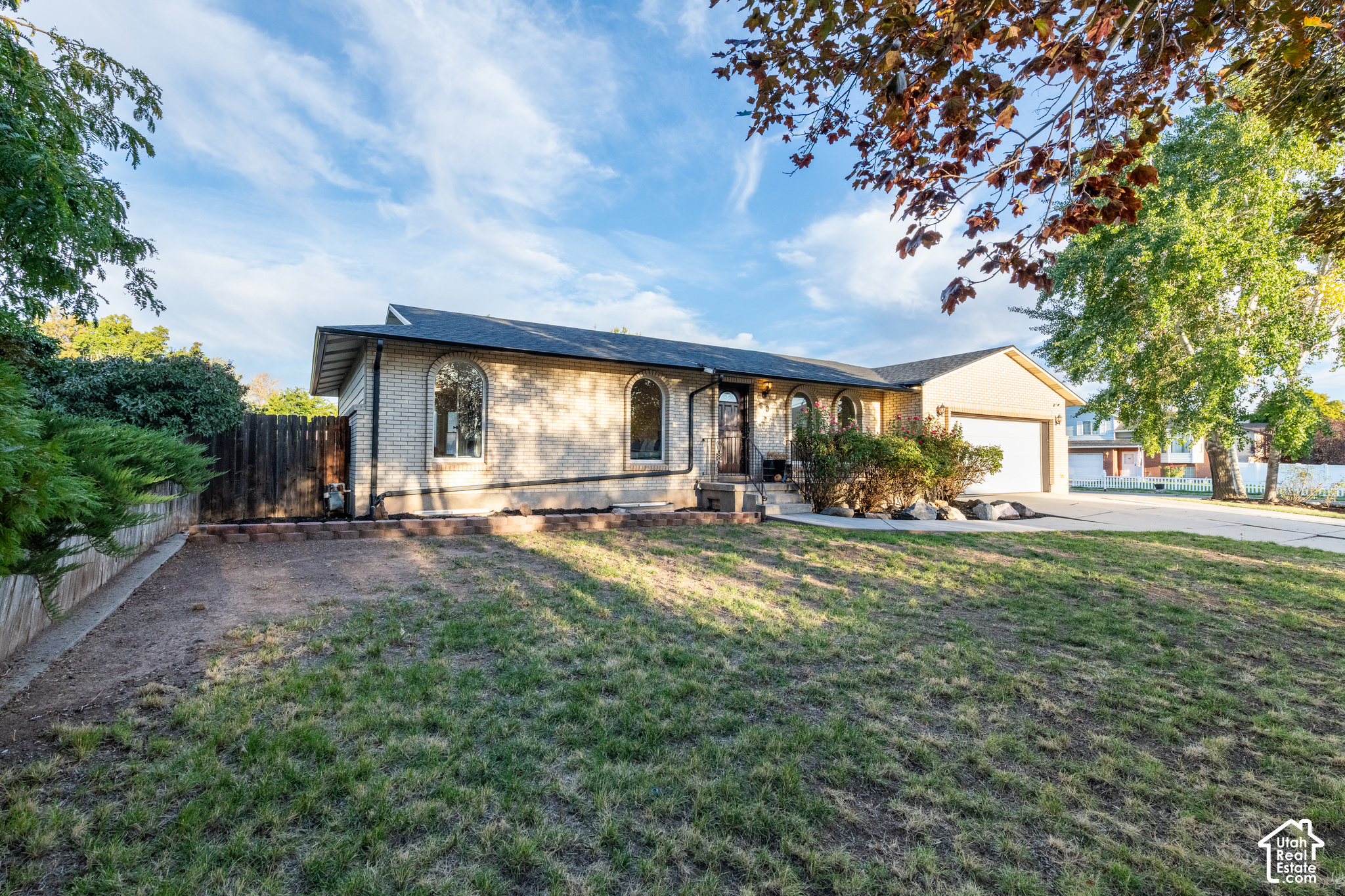 Single-story brick home with arched windows, an attached garage, and a broad front yard.