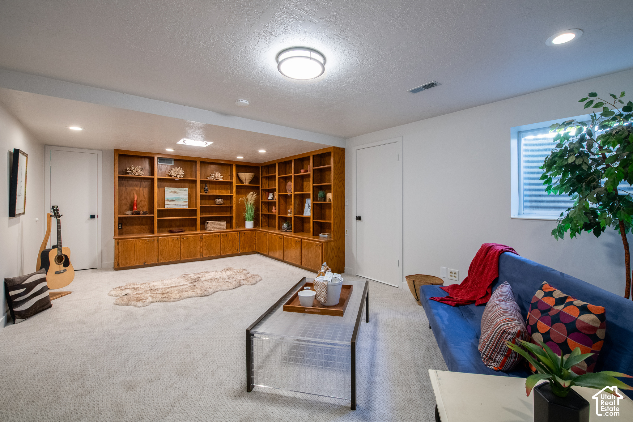 Living room with built-in wood shelving, blue sofa, and white carpet.