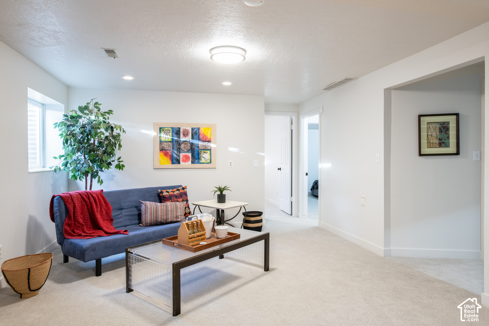 Staged living room with a blue sofa, red throw, and large window.