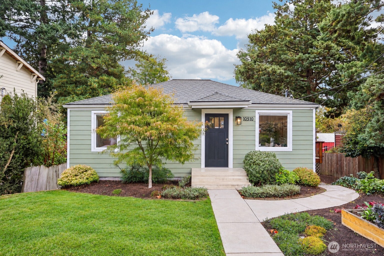 Pale green single-story Seattle home with a dark front door and landscaped yard.