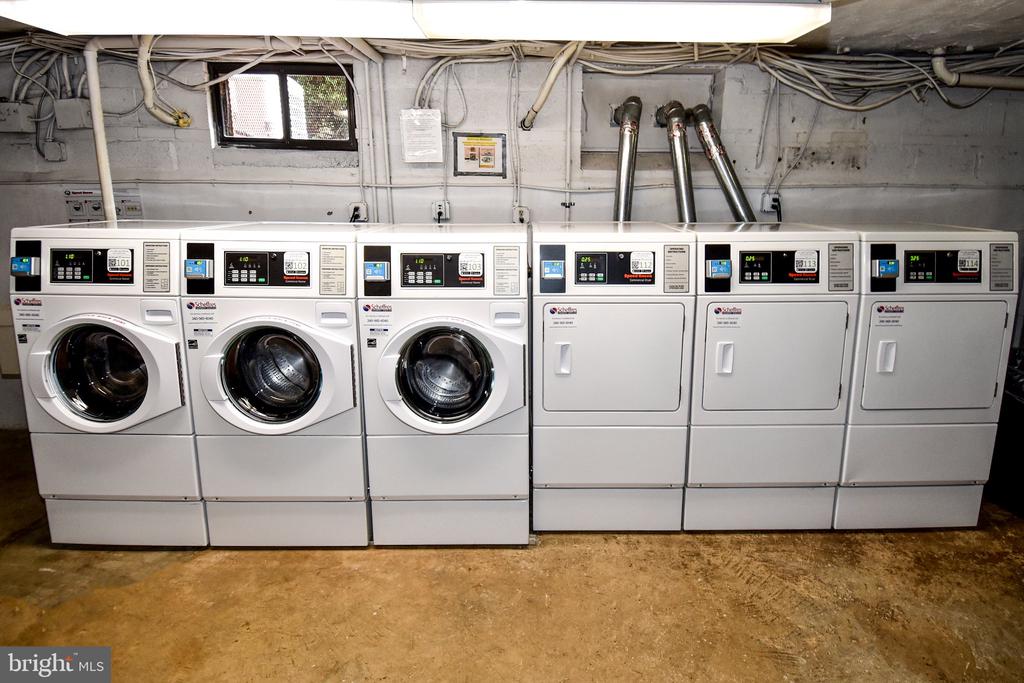 Shared laundry room with three front-loading washers and three commercial dryers.