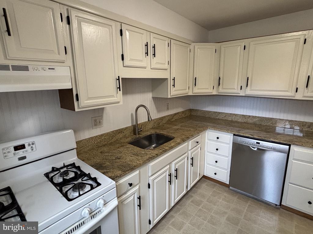 Kitchen with white cabinets, granite counters, and a stainless steel dishwasher.