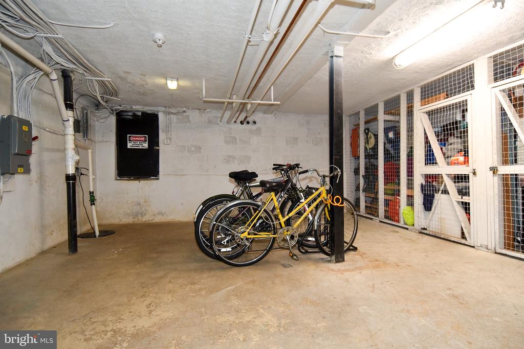 Basement storage area with wire-mesh cages and several bicycles.