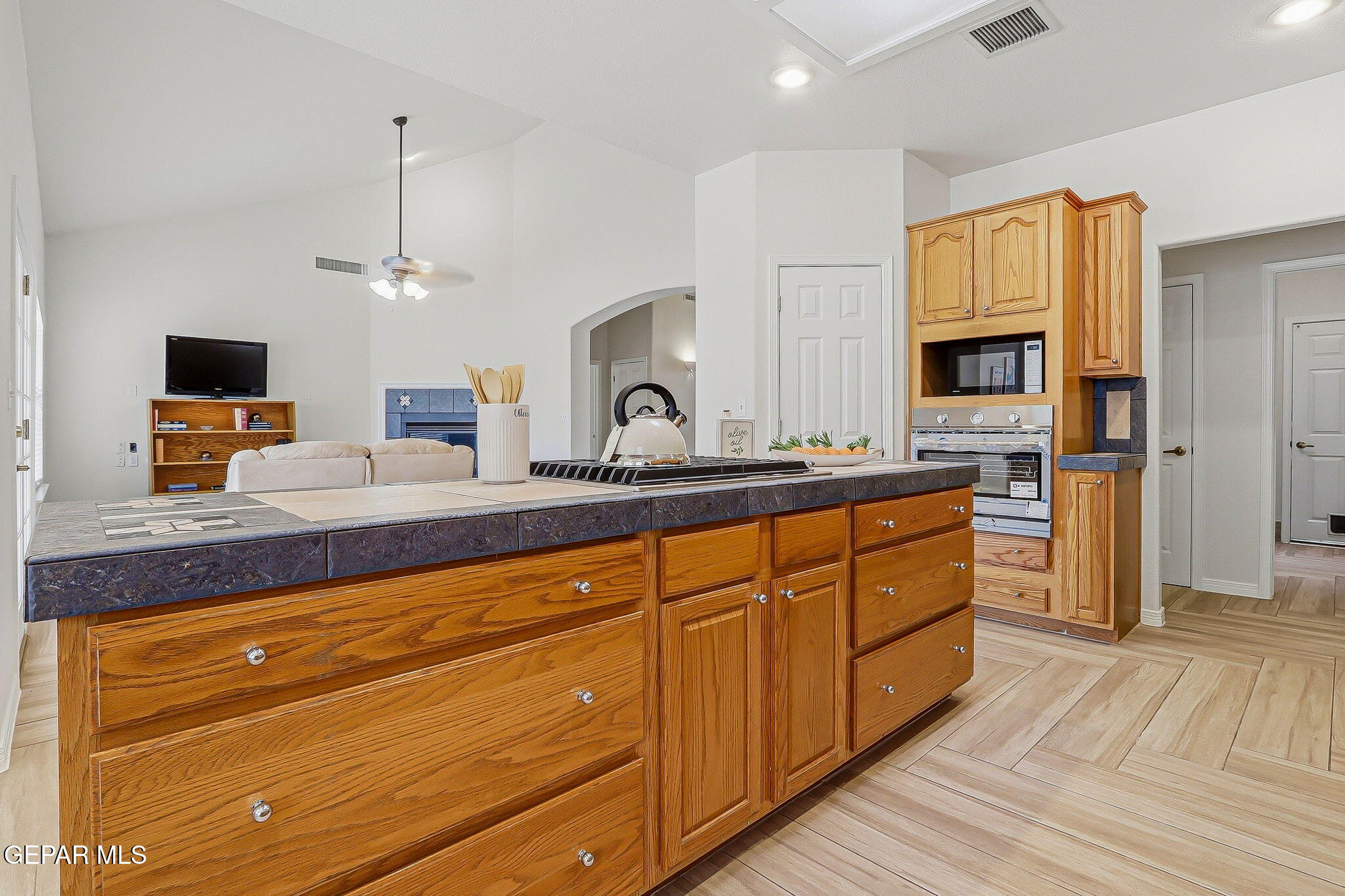 Kitchen with a large wood island, dark tile countertop, and built-in wall oven and microwave.