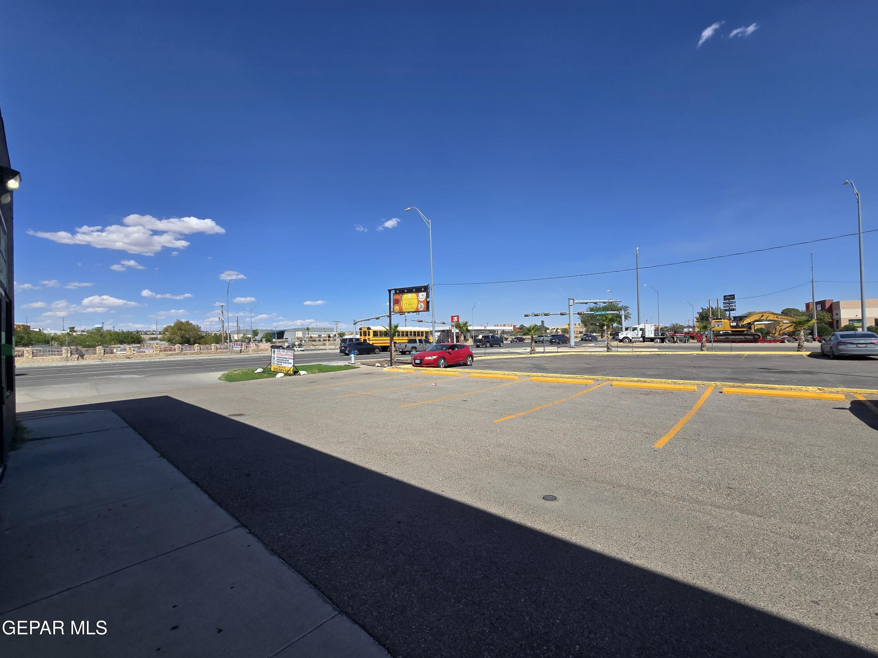 Commercial parking lot with yellow parking lines beside a busy road and nearby businesses.