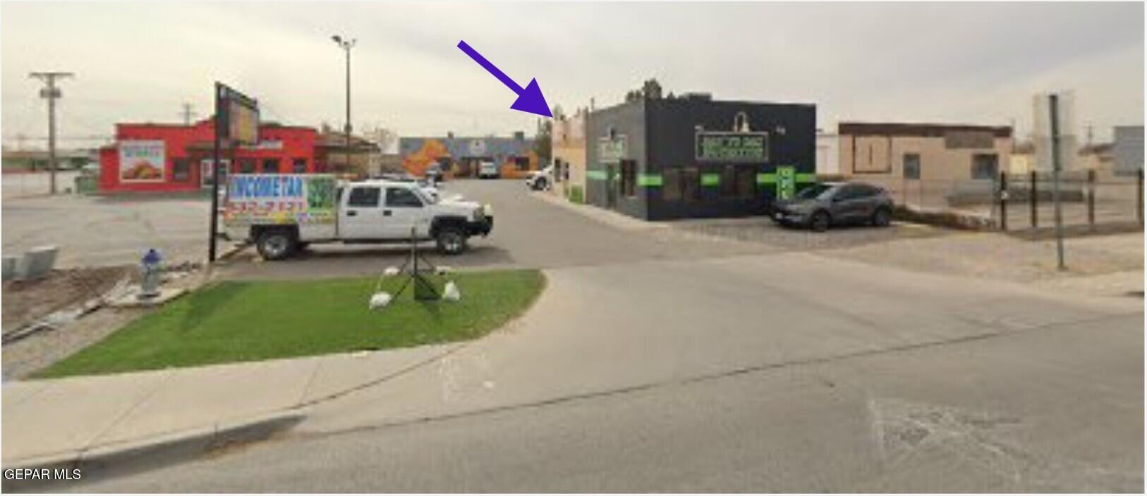 Commercial storefront property beside a dark building, marked by a purple arrow.
