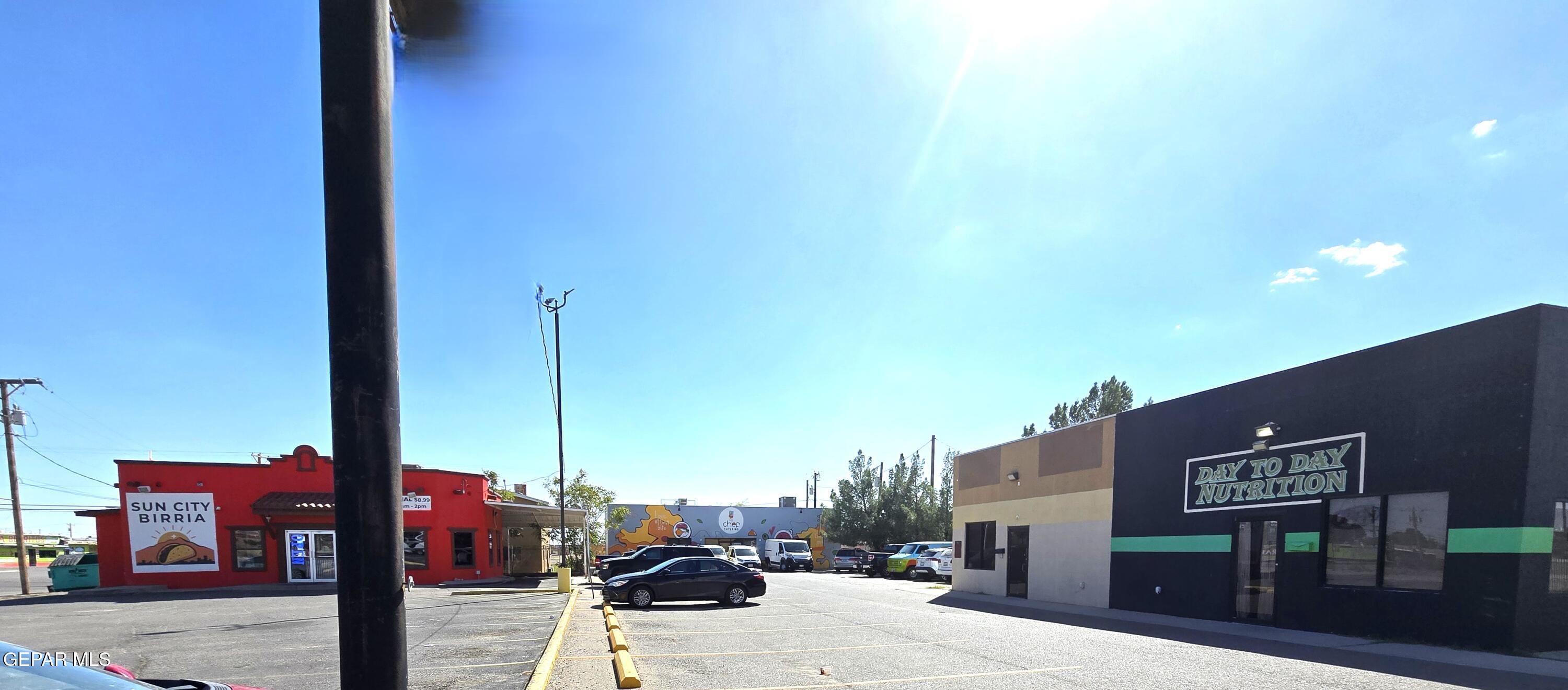 Commercial storefront and parking lot with a black facade and green stripe.