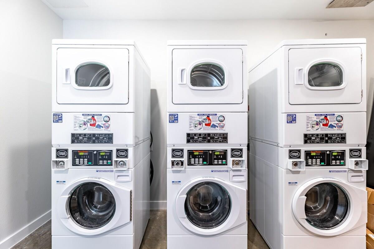 Laundry room with three white stacked commercial washer-dryer units.
