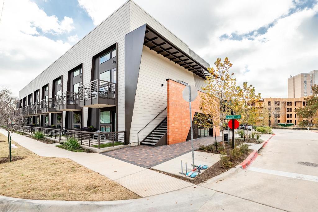 Modern two-story condominium building with metal balconies and a brick corner accent.