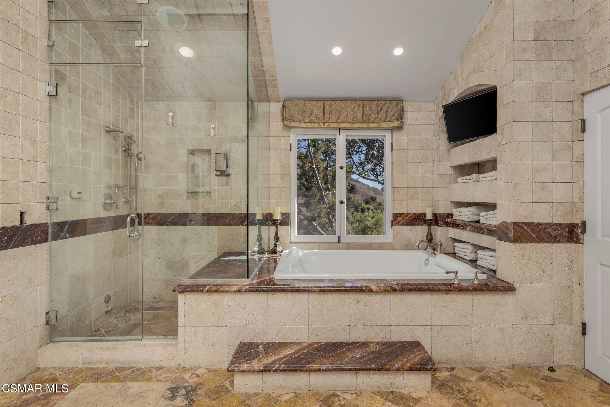 Bathroom with a glass shower, built-in soaking tub, and window overlooking trees.