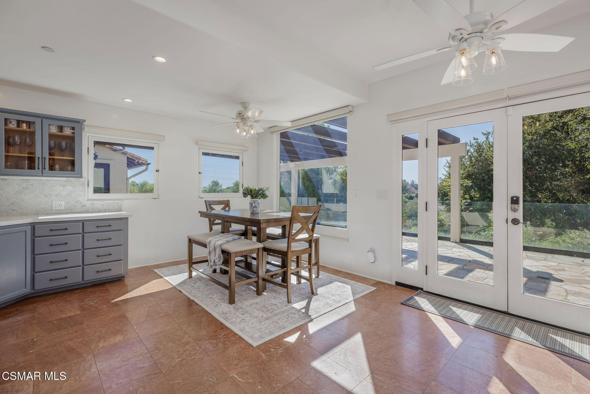 Dining area with gray kitchen cabinetry, a wooden table, and glass patio doors.