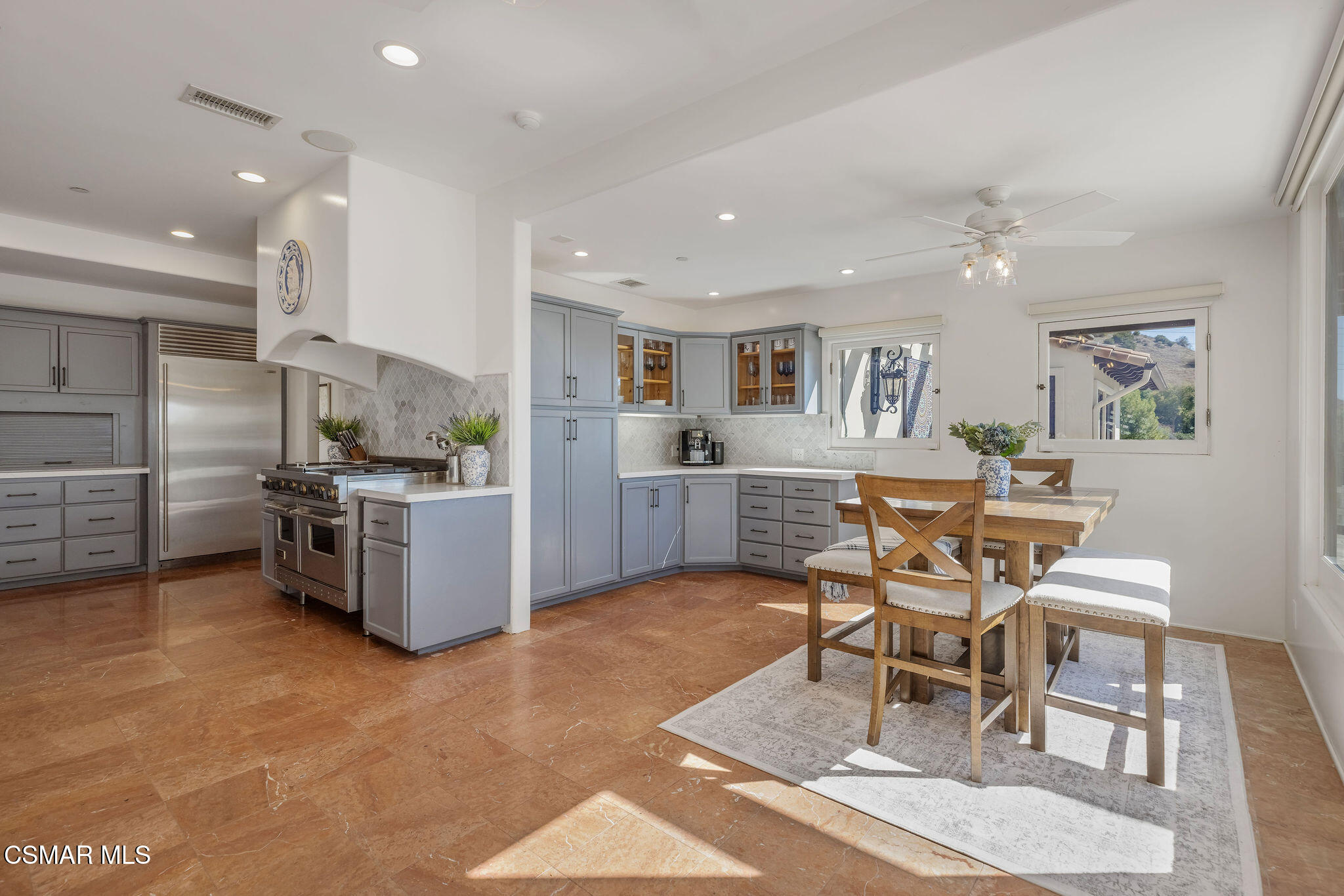 Kitchen and dining area with gray cabinets, stainless steel appliances, and a wood table.