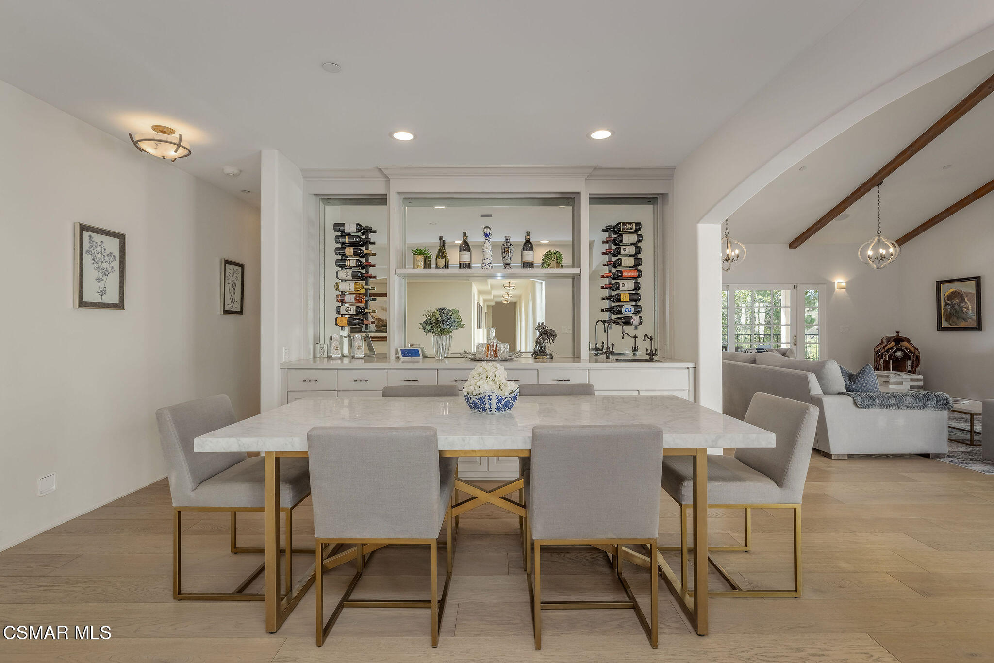 Dining room with a marble table and built-in wine display, opening to a living room.