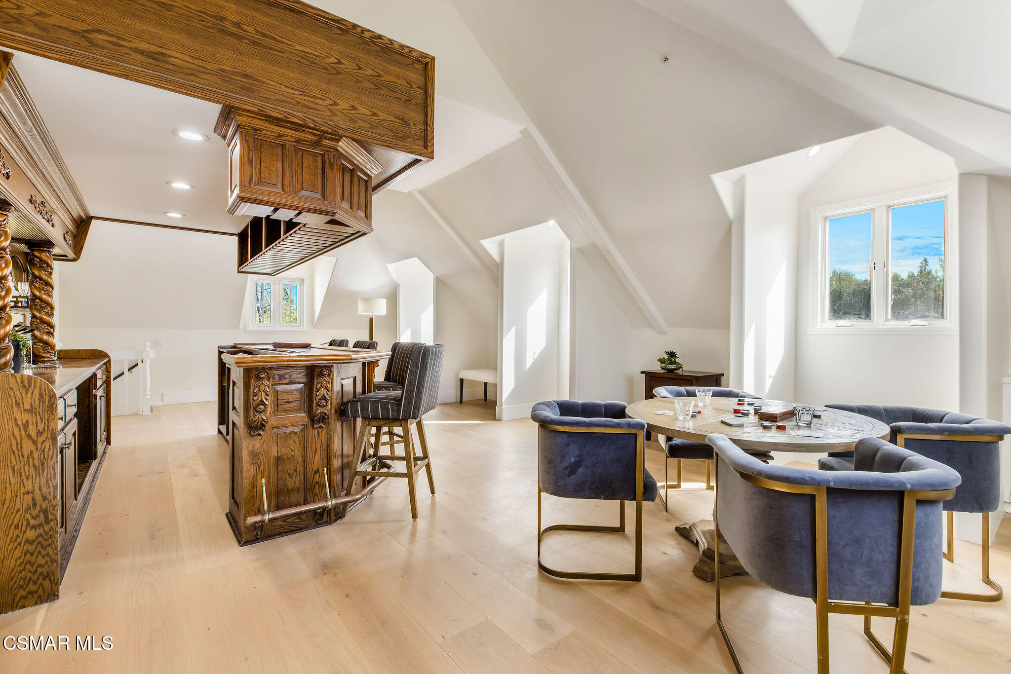 Attic game room with ornate wood cabinetry, a game table, upholstered chairs, and sloped ceilings.