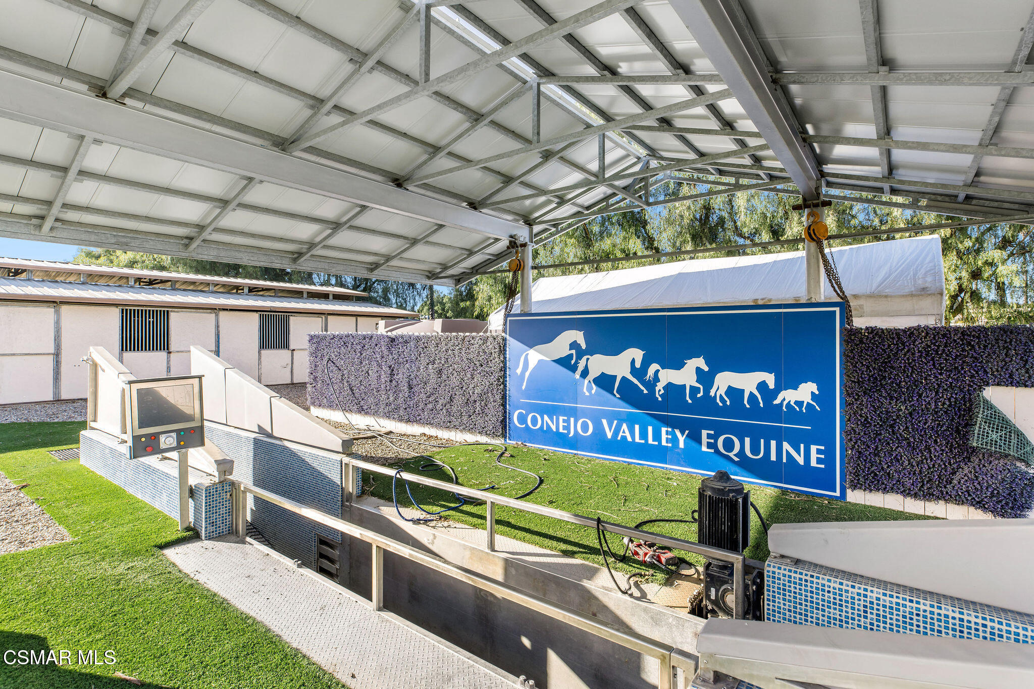 Covered equestrian facility with a Conejo Valley Equine sign and tiled horse-handling equipment.