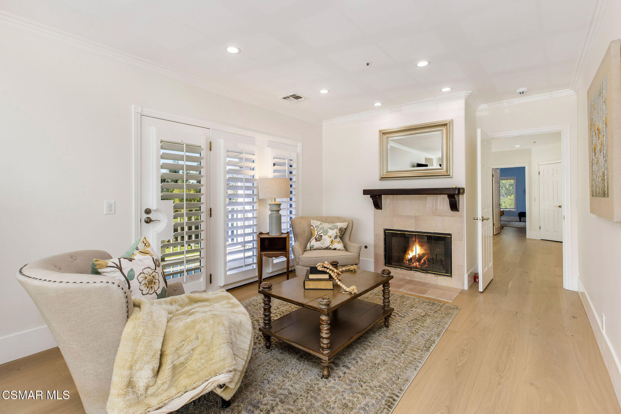 Living room with a lit fireplace, plantation shutters, and comfortable seating.