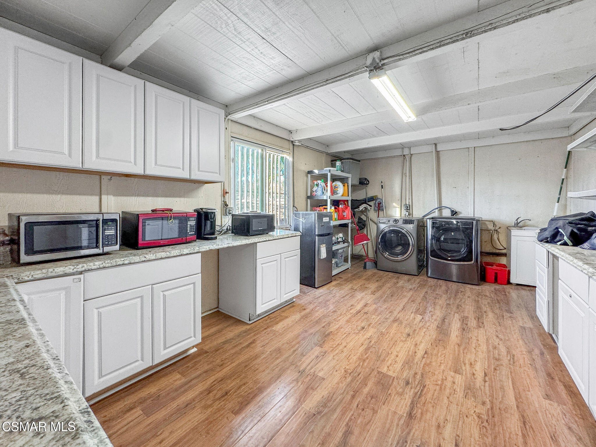 Utility room with white cabinets, wood-look flooring, and side-by-side washer and dryer.