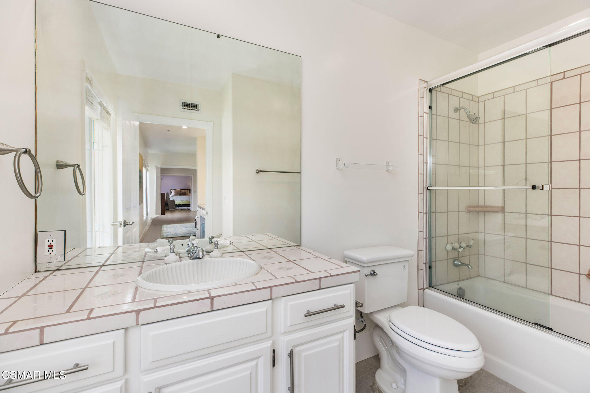 Bathroom with tiled vanity and a glass-enclosed tiled tub and shower.
