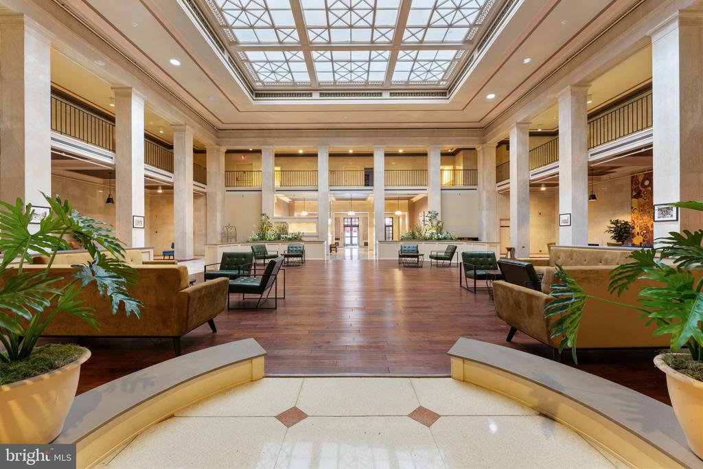 Residential lobby with marble columns, a glass atrium skylight, and seating areas.