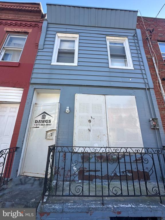 Blue Philadelphia rowhouse with white-trimmed windows and a black iron fence.