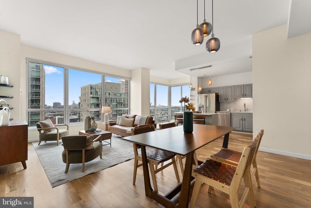 Open-plan condo living and dining area with floor-to-ceiling windows overlooking the city.