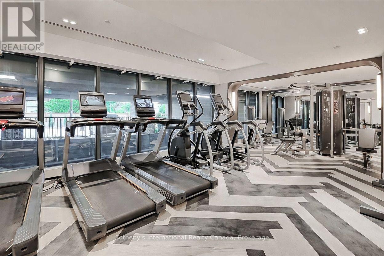 Building fitness room with treadmills and weight machines beside large windows.