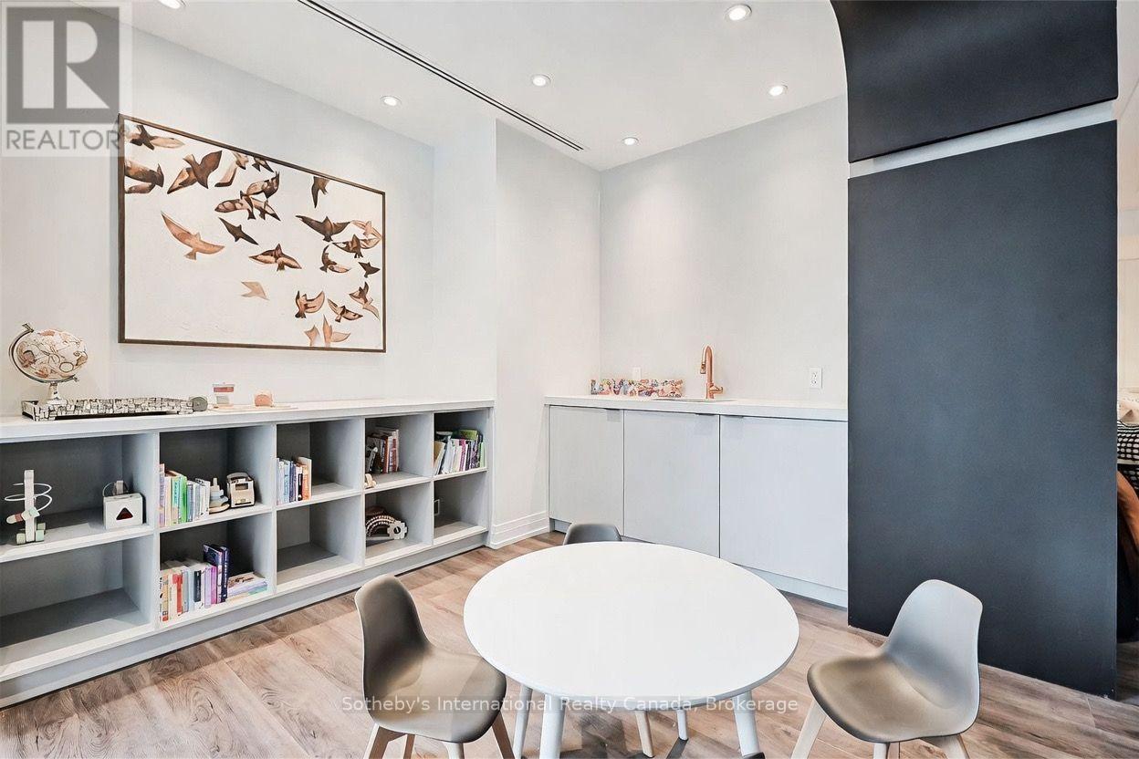 Bright modern room with built-in bookshelves, a round table, gray chairs, and framed bird artwork.