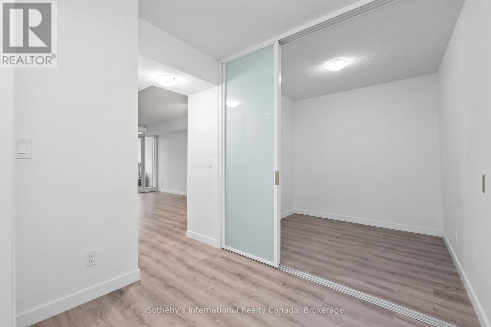 Empty condo room with gray flooring and a frosted-glass sliding partition.