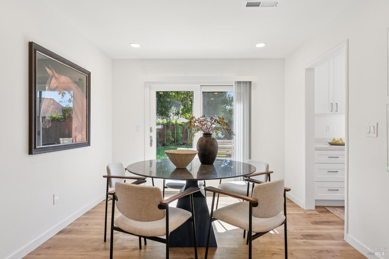 Dining room with a round glass table and sliding doors overlooking the garden.